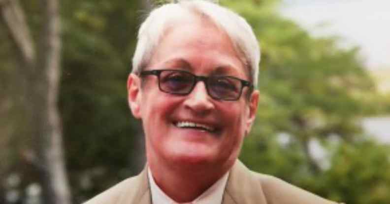 Carmen Vázquez smiles in a beige suit, white shirt and orange tie