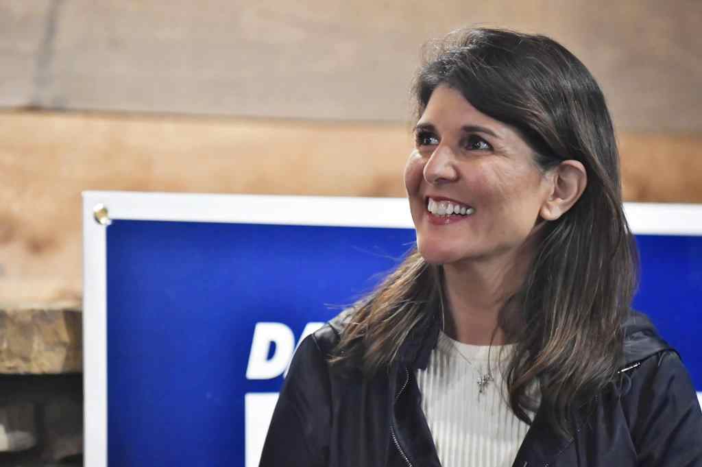 Nikki Haley smiles in a white ribbed top and black jacket