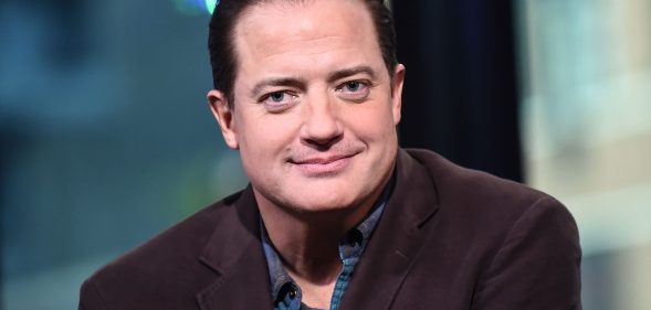 Brendan Fraser smiles at the camera in a blue shirt and black blazer