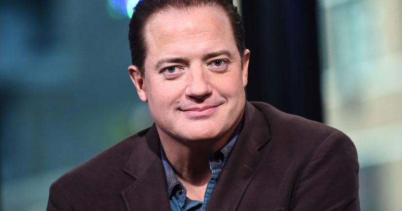 Brendan Fraser smiles at the camera in a blue shirt and black blazer