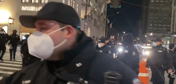 NYPD officers outside Trump Tower. One is close to the camera wearing a face mask