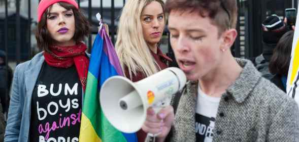 LGBT protestors, one wearing a 'bum boys against Boris' t-shirtm another holding a rainbow Pride flag