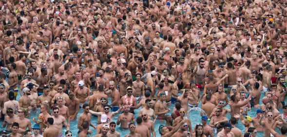 Dozens of men in a pool at a circuit party