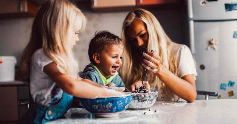A mother and children playing on the kitchen aisle