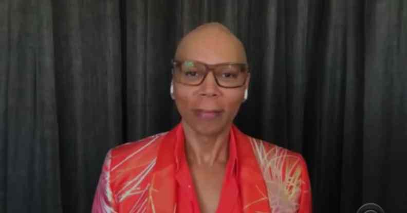 RuPaul out of drag, wearing glasses and a red shirt and blazer