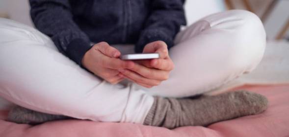 Midsection of unrecognizable young girl smartphone sitting indoors, internet abuse concept.