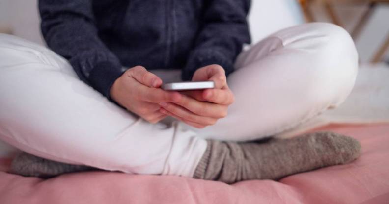 Midsection of unrecognizable young girl smartphone sitting indoors, internet abuse concept.
