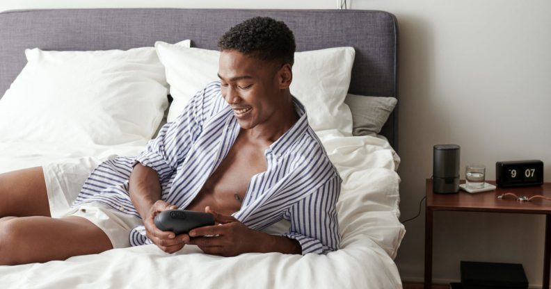 Man lying in bed in boxers and an open shirt holding the Arcwave Ion, a sleek sheath masturbator