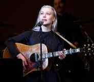 Phoebe Bridgers performs on stage holding a guitar
