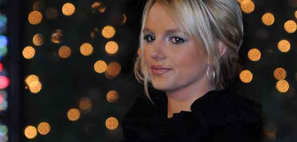 Britney Spears faintly smiles against a backdrop of blurred-out lights