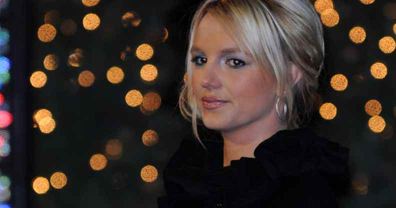 Britney Spears faintly smiles against a backdrop of blurred-out lights