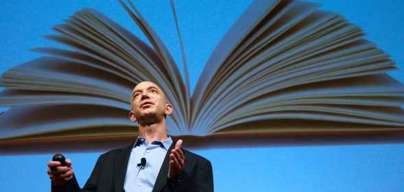 Amazon founder Jeffrey Bezos speaks in front of an image of an opened book