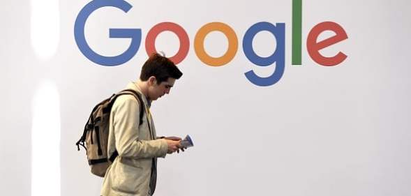 A man walks past the logo of Google