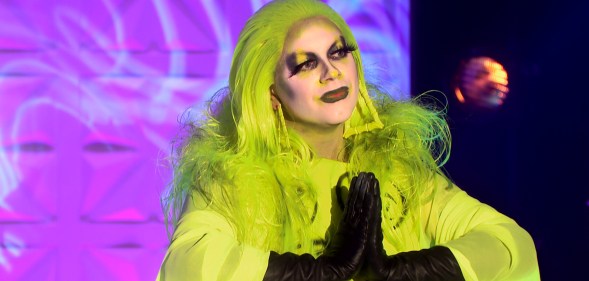 Ginny with her hands together in a prayer motion, wearing a highlighter yellow dress and matching hair