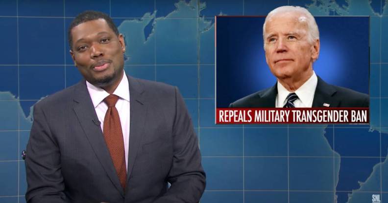 Michael Che hosting Saturday Night Live's "The Weekend Update" with a picture of President Joe Biden in the background with text underneath reading 'repeals military transgender ban'