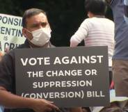 Man holding up sign that reads Vote against the change or suppression (conversion) bill