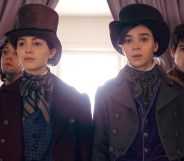 Ella Hunt and Hailee Steinfeld wearing top hats and period garbs in front of a window