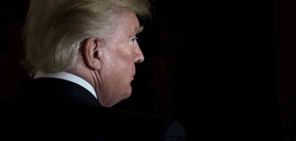Donald Trump looks to his left with only his face lit