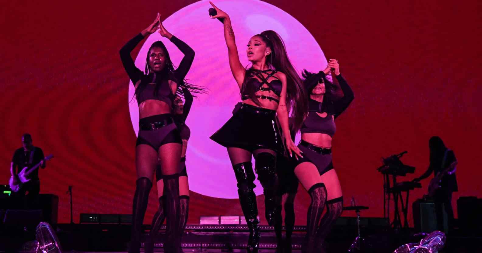 Ariana Grande and dancers on stage, drenched in pink lighting
