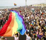 A crowd of pride goers with a giant, long rainbow banner stretching through the crowd