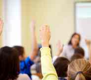 Children raising hands in classroom