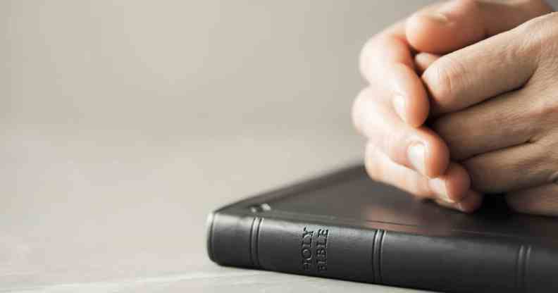 Hands closed in prayer on Holy Bible