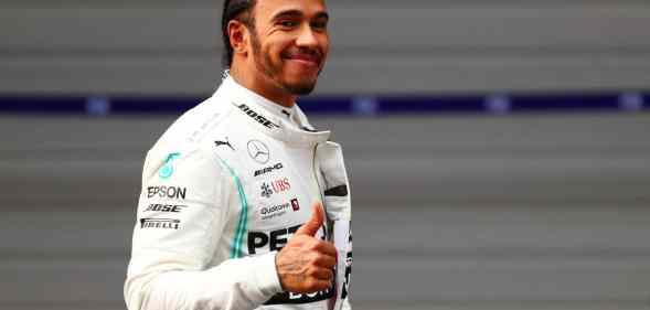Lewis Hamilton in a white racing suit giving a thumbs up