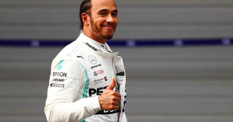 Lewis Hamilton in a white racing suit giving a thumbs up