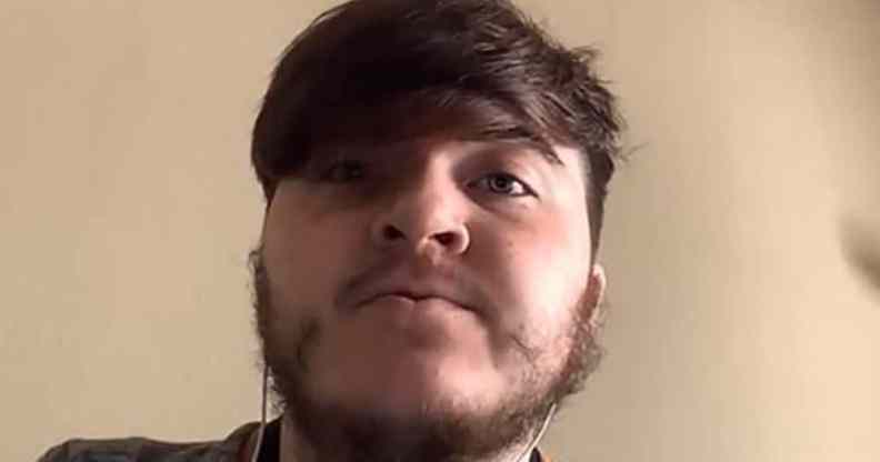 Nick Himely speaks to a web camera against a light brown background