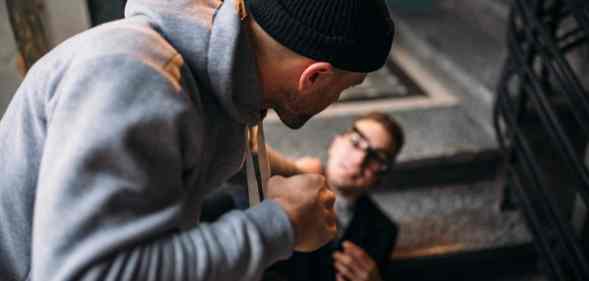 A man wearing a grey top and black hair about to punch a man he is holding by the neck