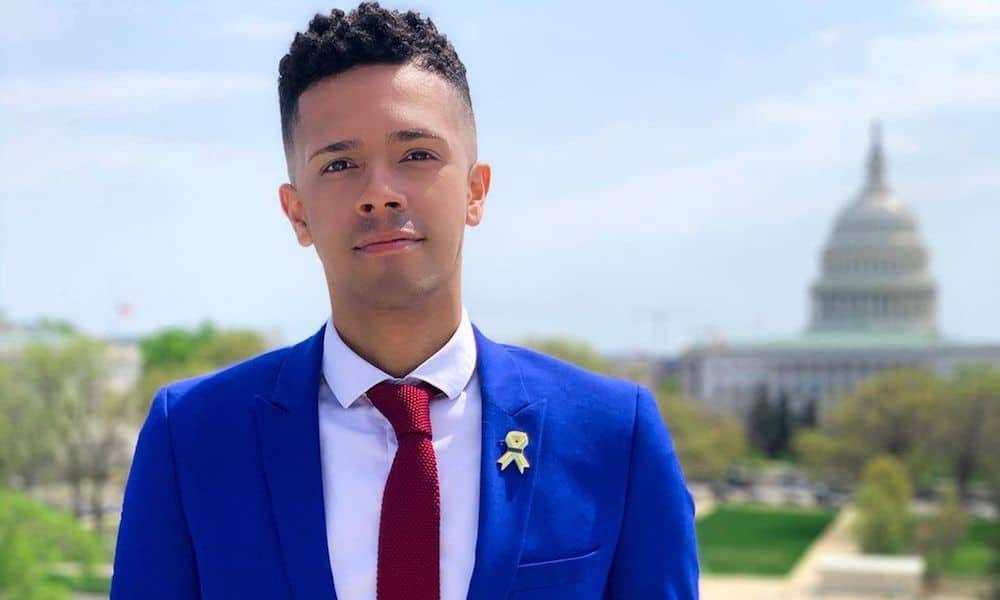 Pulse shooting survivor and gun reform activist Brandon Wolf dressed in a blue suit jacket, white shirt and red tie stands with Washington's Capitol building behind him in the distance