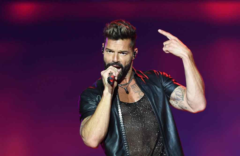 Ricky Martin in a mesh t-shirt and leather top sings into a microphone