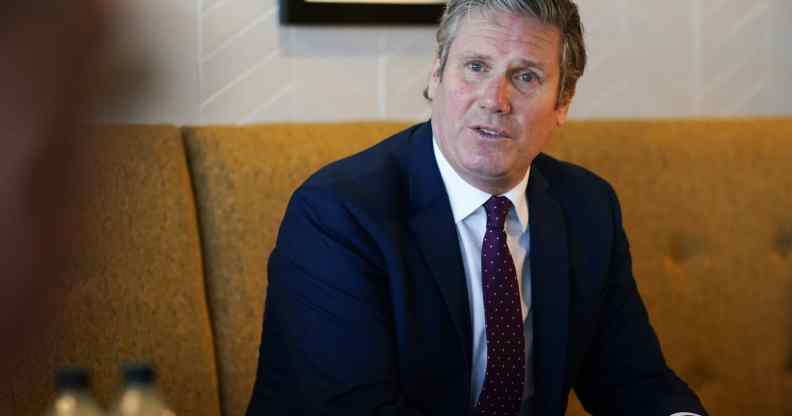 Keir Starmer watches on sat in a cushioned chair wearing a suit