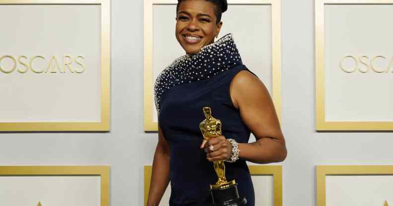 Mia Neal triumphantly holds her Oscar award in a navy dress on the Oscars red carpet