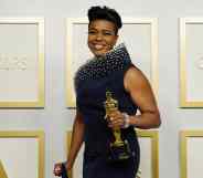 Mia Neal triumphantly holds her Oscar award in a navy dress on the Oscars red carpet