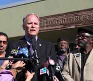 Chris Magnus, a cop in a suit, speaking into reporters' microphones