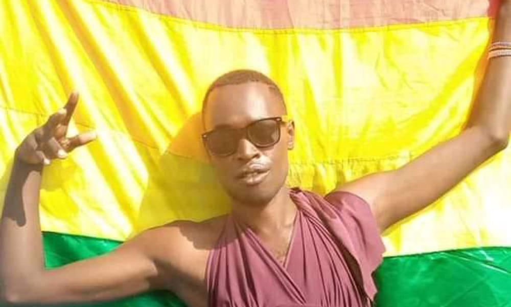 Chriton 'Trinidad Jerry' Atuhwera holds an LGBT+ Pride flag behind him, wearing a pair of sunglasses