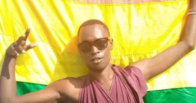Chriton 'Trinidad Jerry' Atuhwera holds an LGBT+ Pride flag behind him, wearing a pair of sunglasses