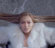 Beyoncé, from above, hanging out of a car window and holding her braids out to the side