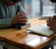 Two people pray with Bibles