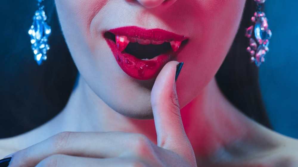 Close-up of a vampire bride wiping blood from her mouth