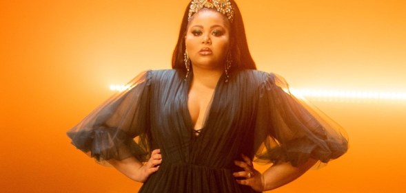 Destiny stands against glowing orange lights with her hands on her waist