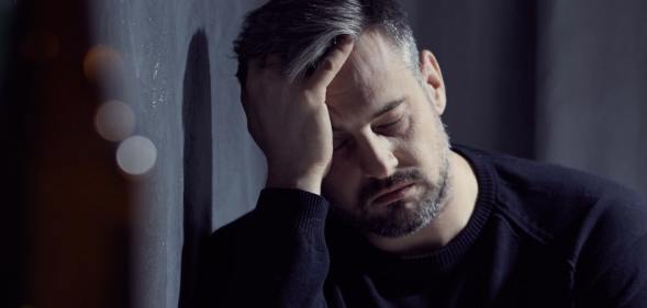 sad man leans against wall