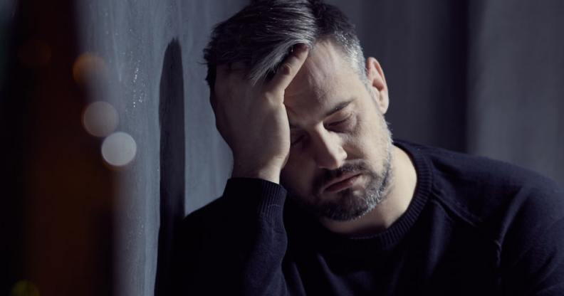 sad man leans against wall