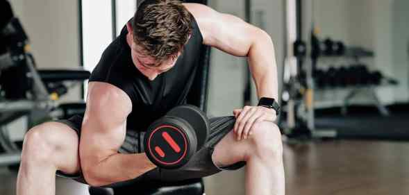Fit young man working out in gym and doing exercises for biceps