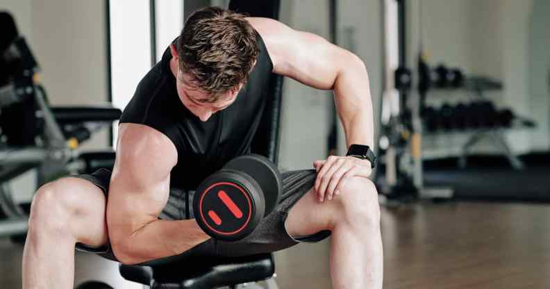 Fit young man working out in gym and doing exercises for biceps