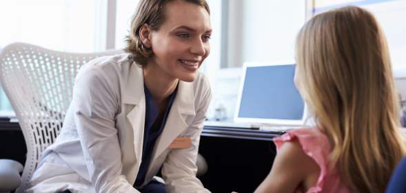A paediatrician sits with a patient.