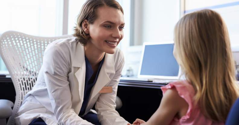 A paediatrician sits with a patient.