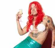 Harry Styles in an Ariel costume, a cigarette in his mouth and holding a flute of champagne
