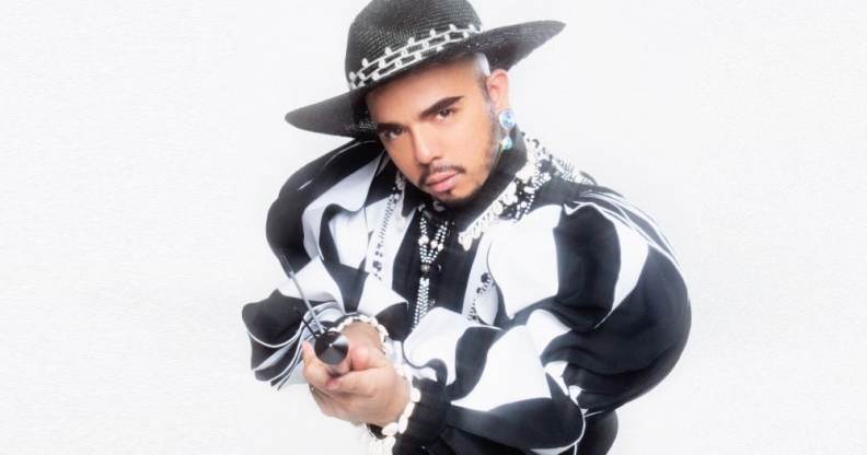 Aja wearing a black and white top with big sleeves, a hat. They're holding a big key